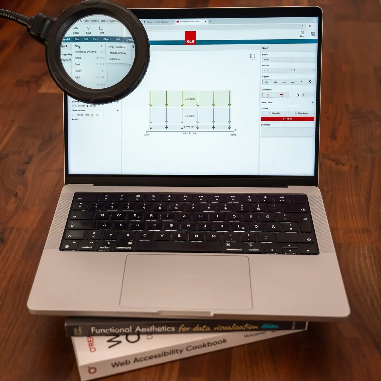 A laptop on accessibility and data visualization books shows a structural diagram, with a magnifying glass enlarging the menu bar.